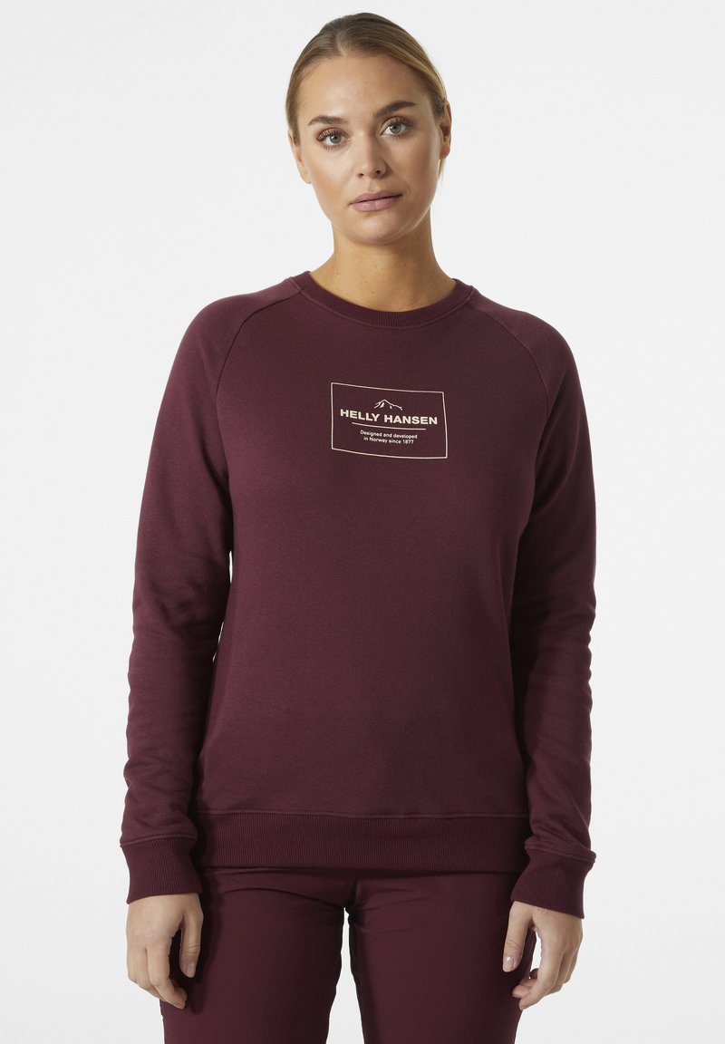 Sudadera burdeos de manga larga y cuello redondo. Presenta un parche central con un logo en texto blanco y beige. Mezcla de algodón con una textura suave.