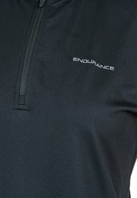 Sort zip-hals atletisk skjorte lavet af glat stof, med et subtilt logo, og en blød tekstur med en tætsiddende design.