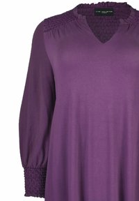 Violet pitkähihaisessa mekossa on V-pääntie, joka sisältää smock-tyylisiä yksityiskohtia olkapäissä ja hihoissa, ja se on valmistettu kevyestä kankaasta.