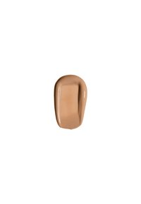 Échantillon de crème cosmétique marron clair, texture lisse, finition brillante, forme irrégulière avec des bords arrondis, sur un fond blanc.