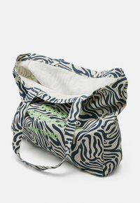 Sac fourre-tout en tissu recyclé avec un motif à rayures zébrées bleu et crème, comportant un texte vert indiquant "FABRIQUÉ À PARTIR DE MATÉRIAUX RECYCLÉS." Texture douce, grande taille.