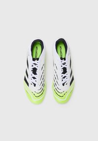 White soccer cleats with black accents and a vibrant green sole. Textured upper with a distinctive design pattern. Laces are white.