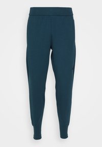Mörk teal tapered träningbyxor med elastisk midja och praktiska mudd vid anklarna, uppställda mot en ren vit bakgrund.