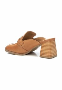 Mules de cuero marrón claro con la parte trasera abierta, que cuentan con una puntera redonda y un tacón block texturizado. Diseño tipo slip-on con una correa decorativa y detalle de hardware.
