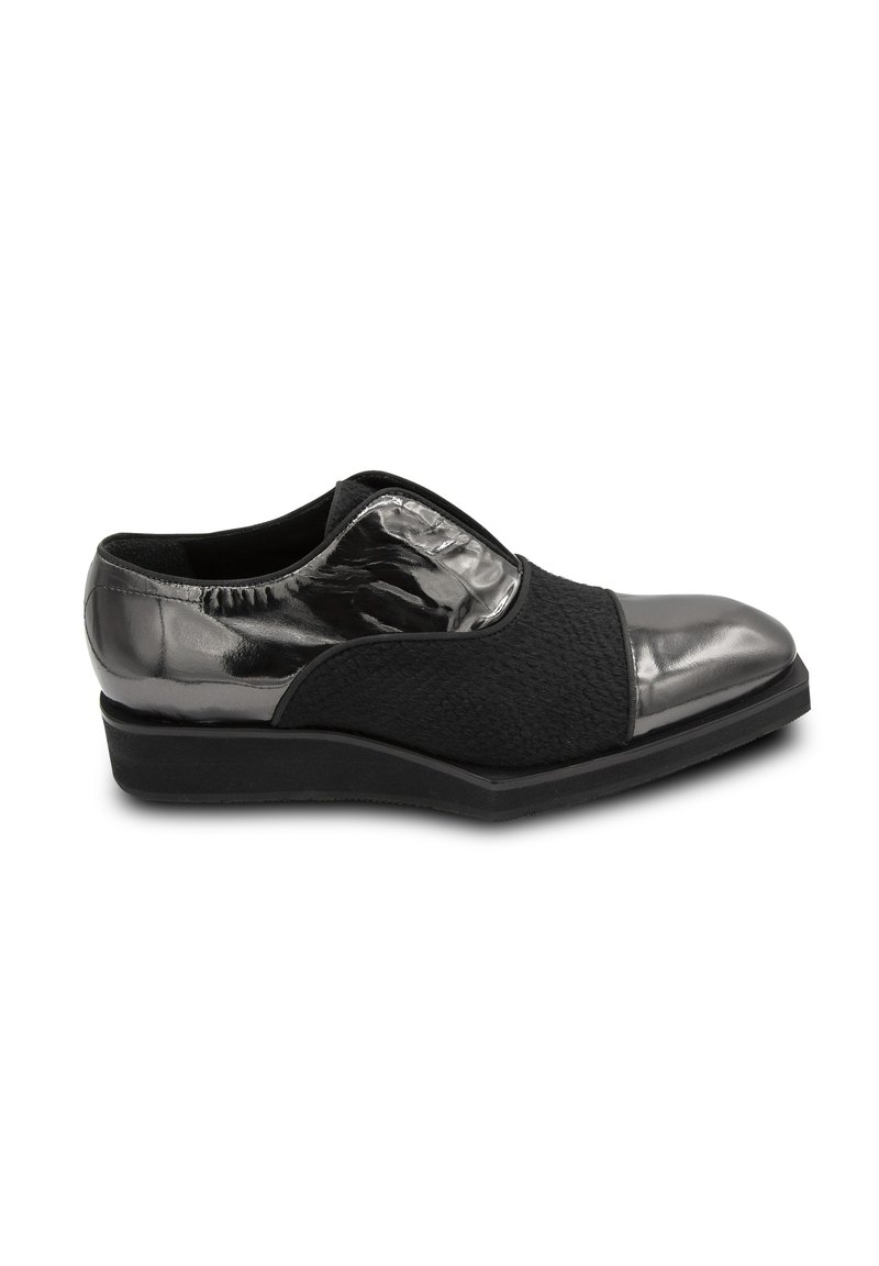 Schwarzer Schuh mit einem Obermaterial aus strukturiertem Stoff und glänzenden metallischen Akzenten an der Zehe und Ferse, ausgestattet mit einer flachen Keilsohle für zusätzlichen Komfort.