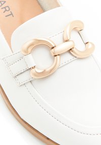 Scarpa bianca in pelle slip-on con un evidente dettaglio in fibbia dorata, con cuciture a vista e punta arrotondata. Design con suola piatta.