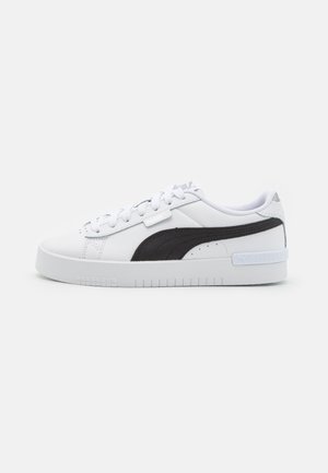Białe sneakersy z czarnym bocznym panelem, górą z teksturowanej skóry, grubą gumową podeszwą i minimalistycznym systemem sznurowania.