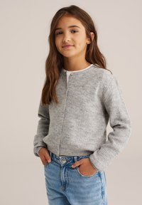 Pelēks ribots kardigāns ar garām piedurknēm un apaļu apkakli, ar pogu aizdari un mīkstu tekstūru, valkāts virs gaiši ziliem džinsiem.