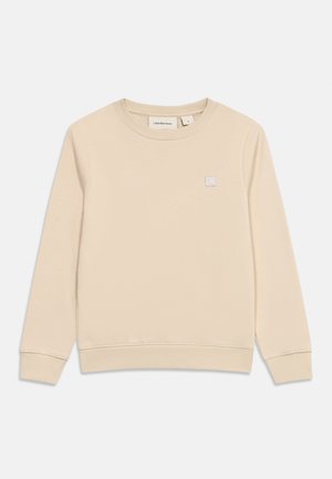 Bež duks dugih rukava s okruglim izrezom, rebrastim manšetama i rubom, s malom zakrpom s logom Calvin Klein Jeans na prsima.