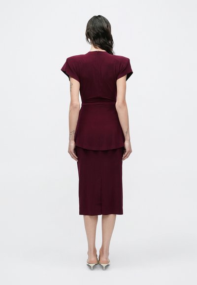 Dopasowana bordowa sukienka z krótkimi rękawkami typu cap, talią z baskinką i spódnicą do kolan z rozcięciem z tyłu. Gładka faktura, minimalistyczny design.