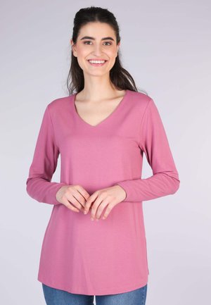 Long-sleeve top in soft, pink cotton with a v-neckline, featuring a relaxed fit and smooth texture. Hem falls below the hips.
