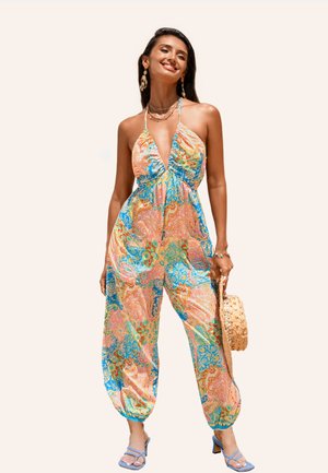 Kleurvolle halter jumpsuit met een patroon in blauw, roze en groen, met baggy broekspijpen en zakken. Gepaard met lichtblauwe hakken en een tas.