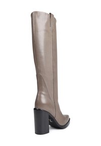 Botte en cuir taupe à talon bloc noir haut, avec bout arrondi, présentée à un angle trois-quarts arrière sur fond blanc.