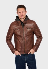 Bruine leren jas met ritssluiting, twee voorzakken en schouderaccenten. Het interieur heeft een grijze capuchon, wat de veelzijdigheid van het ontwerp vergroot.