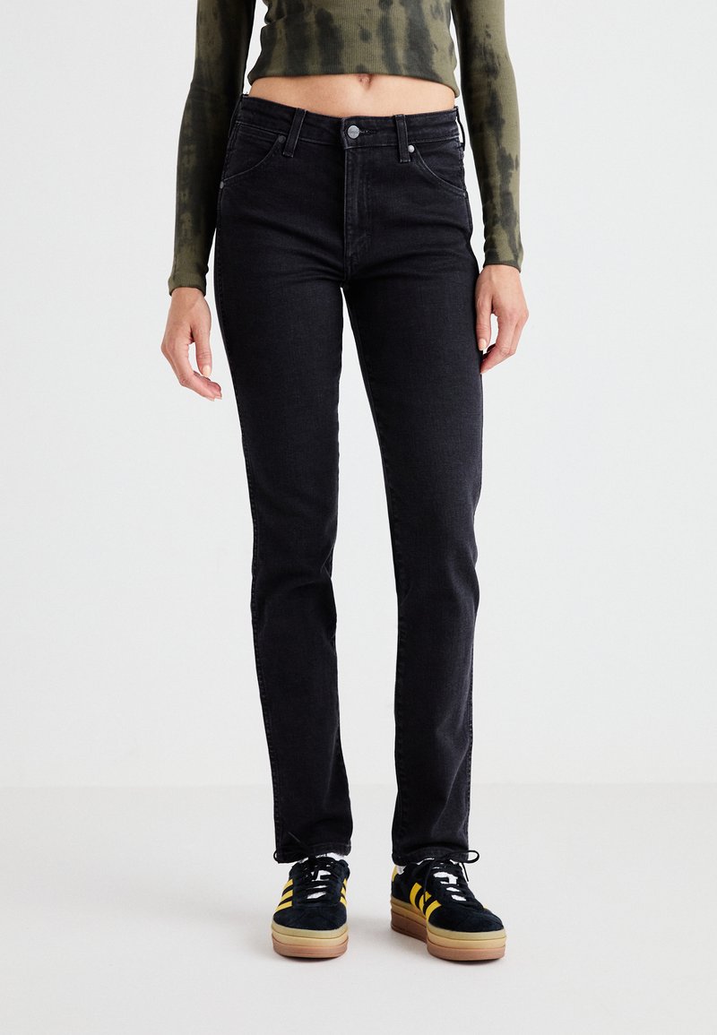 Fekete farmernadrág slim fit szabással, klasszikus ötpocketes dizájnnal, fém szegecsekkel és finom textúrával. Sötét cipőkkel párosítva.