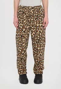 Leopard print pants in tan, brown, and black hues. Features an elastic waistband and cuffed ankles, made from a lightweight fabric.