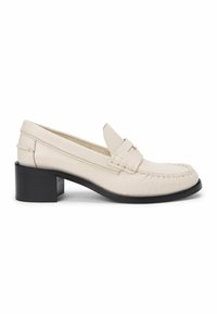Mocassin en cuir couleur crème avec talon bloc noir et détails cousus le long de l\'orteil et des côtés.