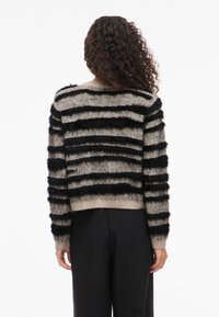 Sweater riscado com uma textura felpuda e faixas alternadas em preto e bege. Corte cropped, mangas longas, punhos e barra canelados.