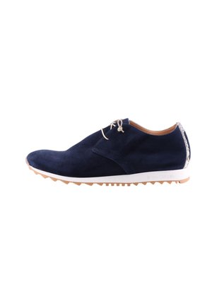 Navy blue suede casual shoe with beige laces, white sole, tan tread, and snake-patterned heel accent, viewed from the side.