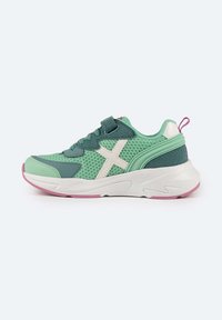 Sneaker in rete verde con dettagli bianchi, suola rosa e sovrapposizioni testurizzate. Presenta un design con lacci e un occhiello sul tallone.