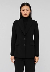 Czarna, dopasowana marynarka o jednorzędowym kroju, z klapami z wycięciami, dwoma przednimi kieszeniami i dwoma czarnymi guzikami. Gładka faktura tkaniny.