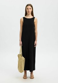 Juodas suknelės maxi modelis be rankovių, pagamintas iš minkštos medžiagos, su apvaliu kaklo iškirpimu. Derinama su nertine smėline spalvos rankine ir plokščiais sandalais.