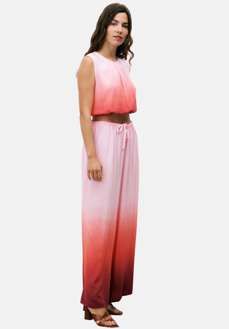 Zweiteiliges Outfit, bestehend aus einem ärmellosen Cropped-Top und hochtaillierten Hosen, mit einem Farbverlauf von hellrosa zu tiefrot.