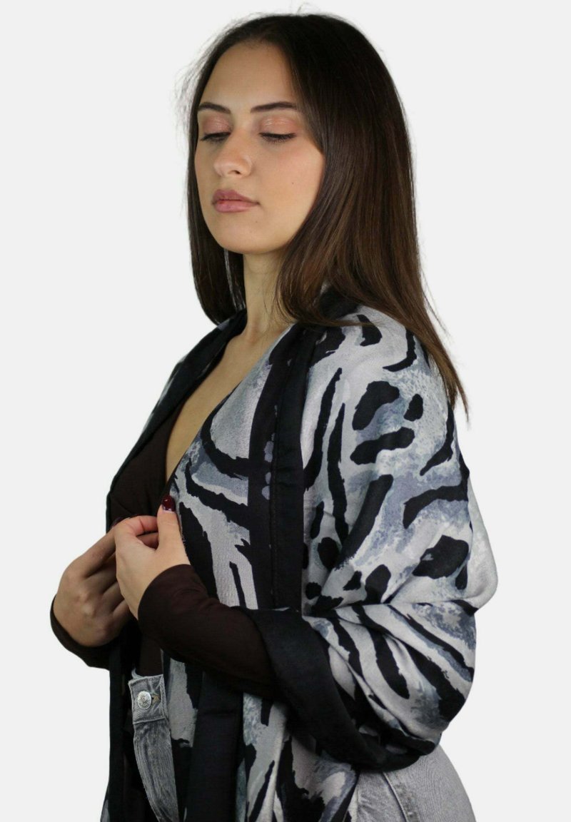 Châle noir et gris à motifs avec une texture douce, présentant des dessins abstraits. Le châle est bordé d'une bordure noire contrastante.