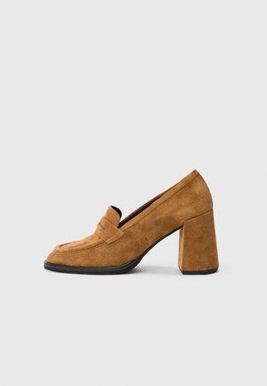 Brown suede block heel loafer with rounded toe and stitched strap detail, shown on plain white background.
