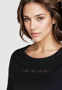 Schwarzes Baumwoll-T-Shirt mit Rundhalsausschnitt und buntem "WIR SIND GLÜCKLICH"-Textdesign auf der Vorderseite, mit lockerer Passform.