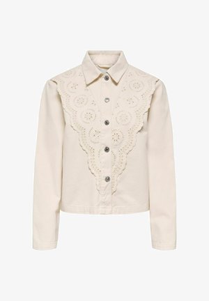 Krēmkrāsas blūze ar garām piedurknēm, ar pogām priekšpusē un V veida krokotu izšuvumu ar caurumiem krūšu un plecu daļā.