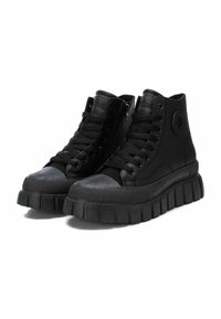 Zapatillas altas negras con una suela gruesa y estriada, material sintético liso, cordones en la parte frontal y detalles de cremallera en el lateral.
