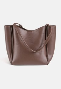 Braune Ledertasche mit breiten Schulterriemen und leicht geschwungenem oberen Rand vor hellem Hintergrund.