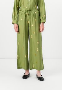 Zeleno oblačilo s širokimi hlačnicami in usklajeno srajco z vzorci zlatih listov. Iz mehke tkanine, z elastičnim pasom in gumbi.