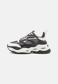 Svart och vit sneaker med en strukturerad mesh-övre, vadderad krage, framträdande sula med utskärningar och kontrasterande gummiaccenter.