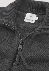 Kohle-grauer Zip-Pullover mit geripptem Kragen und Bündchen, mit einer glatten Textur und Reißverschlussdetails. Mit dem Aufdruck "hessnatur."