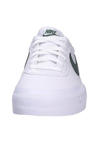 Zapatilla blanca con suela de goma texturizada, parte delantera con cordones y un logo de swoosh de Nike en verde en el lateral. Material superior sintético suave.