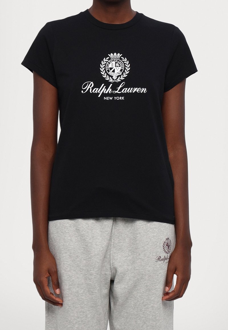Camiseta de algodón negra con mangas cortas que presenta un logo blanco de 'Ralph Lauren New York' rodeado por un diseño circular de laurel.