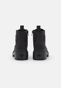 Czarne botki za kostkę z płóciennym wierzchem, wyraźnym logo po boku, dwoma zamkami błyskawicznymi oraz grubą gumową podeszwą zapewniającą przyczepność.