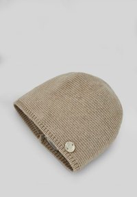 Bonnet en tricot beige avec un motif texturé, un dessus arrondi et un détail en bouton sur le côté. Matériau doux, avec un design ajusté.