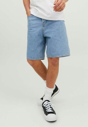 Jasnoniebieskie szorty dżinsowe o luźnym kroju, z surowym wykończeniem i klasycznym pięciopocketowym designem. W zestawie z czarnymi trampkami i białymi skarpetkami do kostek.