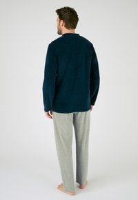 Camiseta de manga larga de forro polar de marina combinada con pantalones ligeros de color gris claro. Textura suave, diseño relajado y costuras sencillas.