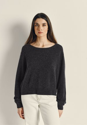 Dark gray knit sweater with a wide neckline and long sleeves, paired with light-colored jeans, featuring a relaxed fit and soft texture.