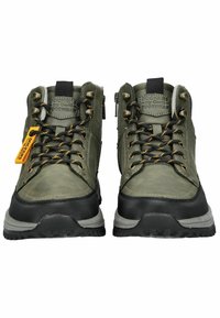 Botas de senderismo verdes con una suela de goma negra y resistente, ojales metálicos y etiqueta amarilla. Presentan un sistema de cordones en la parte delantera y un cuello acolchado para mayor comodidad.