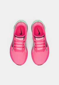 Une paire de chaussures de course Nike de couleur rose vif et vert menthe avec des logos swoosh noirs, vue de dessus sur un fond blanc.