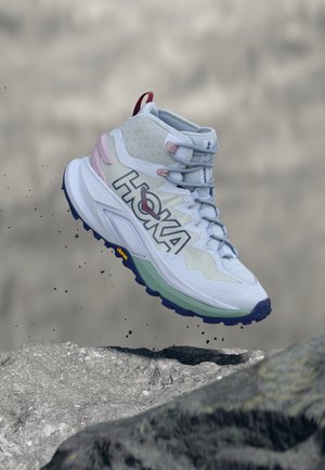 Chaussure de randonnée montante avec une tige en mesh gris clair, des accents roses et une semelle extérieure multicolore à motif de crampons robuste.