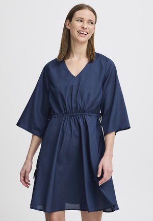 Robe bleu marine avec un décolleté en V, des manches larges et une taille élastique avec des liens. Tissu doux avec une silhouette fluide.