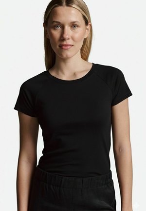 Schwarzes, tailliertes T-Shirt mit kurzen Raglanärmeln, rundem Halsausschnitt und glatter Textur, kombiniert mit lockeren schwarzen Hosen.