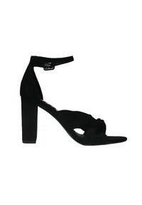Zwarte suède sandaal met hoge hakken en een stevige blokhak, open teen en enkelbandje. Kenmerkt een gedraaid ontwerp aan de voorkant.