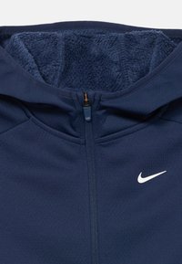 Jūras spēku zip-up džemperis ar mīkstu flīsa odere. Iespējas augsts apkakle un baltais Nike logo kreisajā krūtī. Gluda, elastīga auduma.